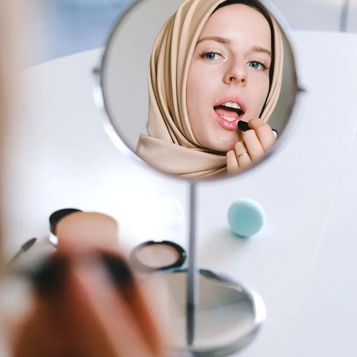 آرایش صورت با حجاب کامل جلوی آینه میز آرایش
